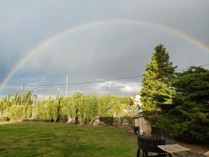 um arco-íris no céu sobre um quintal com um banco em Green House em El Calafate