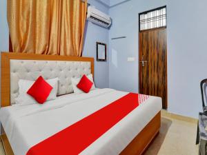 a bedroom with a bed with red pillows and a door at Flagship Hotel Aradhya Galaxy in Bhauli