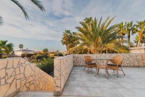 a patio with a table and chairs and palm trees at Villa Helene in Miraflor