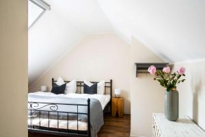 a bedroom with a bed and a vase of pink flowers at Hofgut Mollberg in Wiefelstede