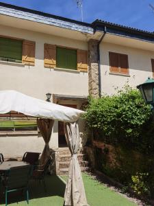 Oteruelo del Valle的住宿－Chalet entero con patio，庭院配有白色遮阳伞和桌子。