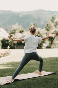 Eine Frau, die auf einer Yogamatte auf dem Gras steht. in der Unterkunft Hotel Rosenhof Murau in Murau