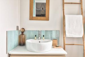 ein Badezimmer mit einem weißen Waschbecken und einem Spiegel in der Unterkunft Cozy and practical apt in the 10th arrondissement in Paris