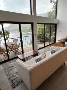 a living room with a couch and large windows at Atitlan Sunset Lodge in Santa Cruz La Laguna