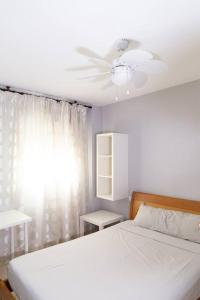 ein Schlafzimmer mit einem weißen Bett und einem Deckenventilator in der Unterkunft Pasquín in Cádiz