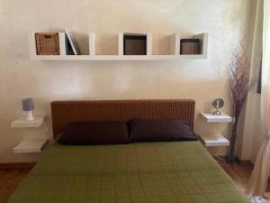 een slaapkamer met een bed met groene lakens en witte planken bij Accogliente appartamento in cascina lombarda in Segrate