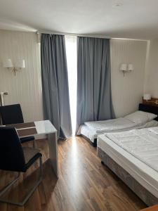 una camera d'albergo con due letti, una scrivania e una finestra di West End Apartments a Francoforte sul Meno