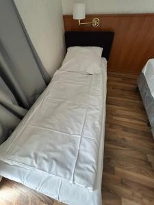 a small bed with white sheets and a wooden floor at West End Apartments in Frankfurt