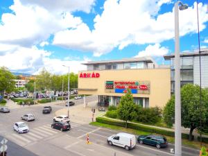 Blick auf ein Einkaufszentrum mit Autos auf einem Parkplatz in der Unterkunft Árkád Apartman-Pécs in Pécs