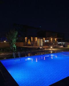 a swimming pool at night with a house in the background at Cebel Tiny House&Bungalovs in Kemer