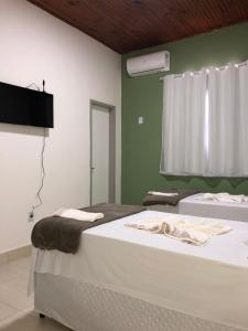 a bedroom with two beds and a tv on the wall at Pousada Salomão in Teixeira de Freitas