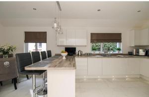 cocina con armarios blancos y encimera de mármol en Home from home en Bexhill