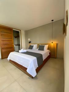 um quarto com uma cama grande e lençóis brancos em Alameda Lounge Pousada em Pôrto de Pedras