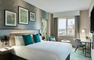 Una habitación de hotel con una cama grande y un escritorio. en Leonardo Royal Hotel Glasgow, en Glasgow