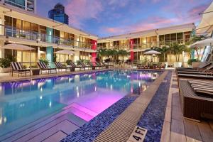 The Gabriel Miami Downtown, Curio Collection by Hilton في ميامي: مسبح الفندق مع الكراسي والمظلات بجانب مبنى