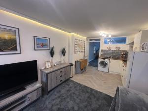 ein Wohnzimmer mit einem Flachbild-TV und eine Küche in der Unterkunft The Annex in Southend-on-Sea