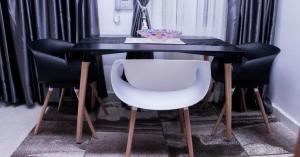 uma mesa preta com quatro cadeiras e uma cadeira branca debaixo dela em JEFA Deluxe Suites em Lagos