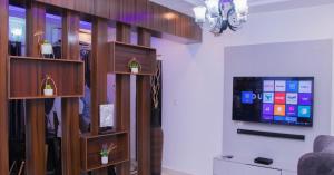 uma sala de estar com uma televisão de ecrã plano e prateleiras de madeira em JEFA Deluxe Suites em Lagos