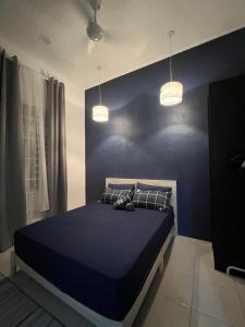 a bedroom with a bed with blue walls and two lights at Majestic Homestay - Pasir Puteh in Pasir Puteh