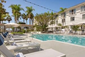 una piscina en un hotel con sillas y sombrillas en Hilton Garden Inn Carlsbad Beach, en Carlsbad