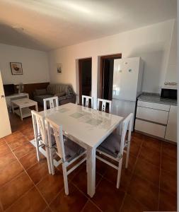 een witte eettafel met stoelen en een keuken bij Villa Lago Mayor in Chiclana de la Frontera