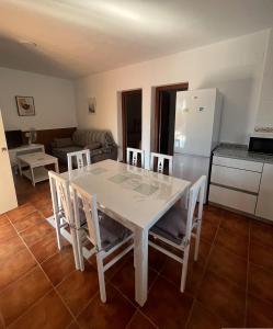 een witte eettafel met stoelen en een keuken bij Villa Lago Mayor in Chiclana de la Frontera