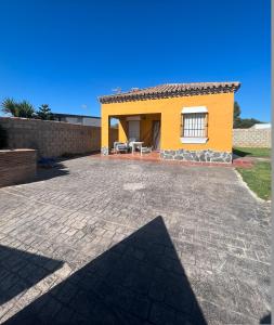 een klein geel huis met een patio ervoor bij Villa Lago Mayor in Chiclana de la Frontera