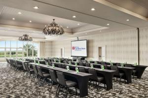 una sala de conferencias con mesas, sillas y una pantalla en Hilton Garden Inn Carlsbad Beach, en Carlsbad