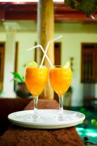 zwei Gläser Orangensaft auf einem Teller in der Unterkunft Dambulla Kings Inn in Dambulla