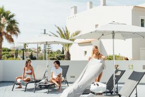 a group of people sitting on a patio with a woman in a dress at Placid Village in Carvoeiro