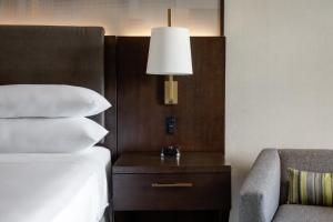 a bedroom with a bed and a lamp and a chair at Dallas-Addison Marriott Quorum by the Galleria in Addison