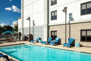 a pool with blue lounge chairs next to a building at Hampton Inn Austin Round Rock in Round Rock