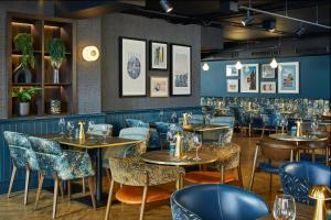 a restaurant with tables and chairs in a room at Leonardo Royal Hotel Edinburgh in Edinburgh