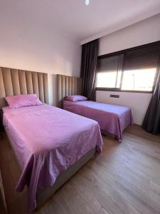 a bedroom with two beds with pink sheets and a window at appartement deux chambres salon 8 in Marrakesh