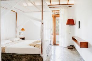 a white bedroom with a bed with a canopy at Amuura Beach Villa in Beruwala