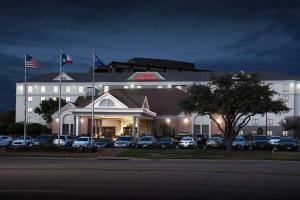 a large white building with cars parked in front of it at Hilton Garden Inn Las Colinas in Irving