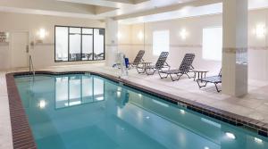 a swimming pool with chairs and tables in a building at Hilton Garden Inn Denver Highlands Ranch in Highlands Ranch