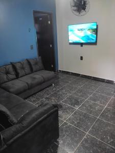 sala de estar con sofá y TV de pantalla plana en Gray House 3 - JD. Leonor en Londrina