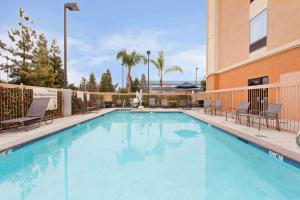 Una piscina con sillas y un edificio. en Hampton Inn & Suites Clovis Airport North, en Clovis