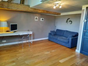 a living room with a blue couch and a desk at La Grange in Savonnières