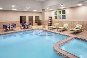 Embassy Suites Fort Worth - Downtown في فورت وورث: مسبح في غرفة الفندق مع كراسي وطاولة