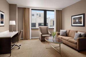 a living room with a couch and a table and a desk at Hilton Indianapolis Hotel & Suites in Indianapolis