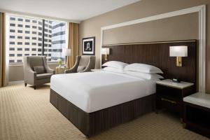 a large bedroom with a large white bed and a chair at Hilton Indianapolis Hotel & Suites in Indianapolis