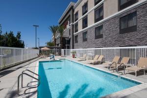 einen Pool mit Stühlen und ein Gebäude in der Unterkunft Hampton Inn Los Angeles Orange County Cypress in Cypress