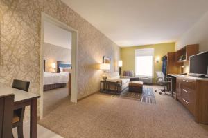 a hotel room with a bedroom with a bed and a desk at Home2 Suites by Hilton Parc Lafayette in Lafayette