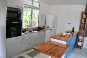 cocina con armarios blancos y encimera de madera en TEVIHOUSE 2 Bedrooms House or-and Bungalow with Pool en Taravao