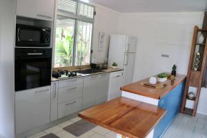 a kitchen with white cabinets and a wooden counter top at TEVIHOUSE 2 Bedrooms House or-and Bungalow with Pool in Taravao