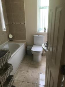 a bathroom with a tub and a toilet and a sink at Sleeps 8 Matlock/ Matlock Bath Pet Friendly in Matlock Bank