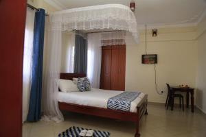 a bedroom with a bed with a canopy at Jatheo Hotel Rwentondo in Mbarara
