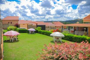 um quintal com mesas e guarda-chuvas na relva em Jatheo Hotel Rwentondo em Mbarara